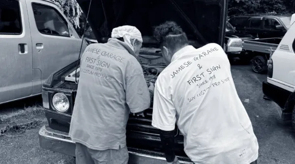 エンジンを確認する整備士2人が車のボンネット内を覗き込む様子