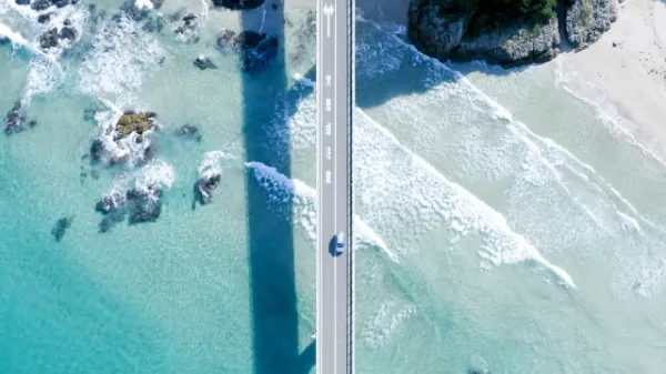 エメラルドグリーンの海の上に架かる橋を真上から撮影した空撮写真