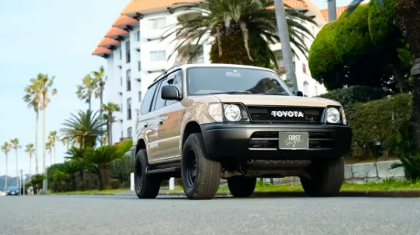 TOYOTAのSUV車両がヤシの木と白い建物の前に停車