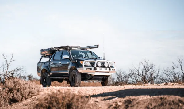 砂利道の上に停車した装備満載の黒いオフロードピックアップトラック