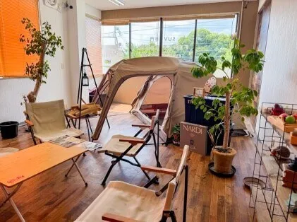 室内にキャンプギアが並べられた展示スペースと設営されたテント