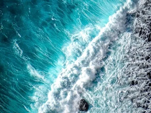 上空から撮影されたエメラルドグリーンの海と白波の様子