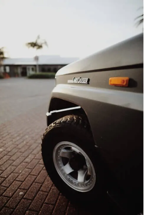 レンガの地面に停車したトヨタ・ランドクルーザーの前輪部分