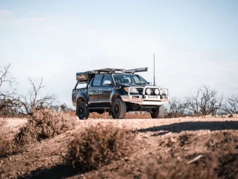 サバンナ風の乾燥地帯を走るキャンピング仕様のトヨタ四駆
