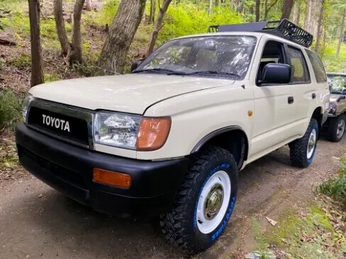 山道に停車するクリーム色のトヨタSUVと森林の背景